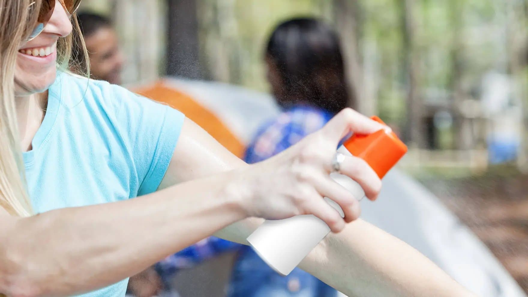 Mujer rociándose repelente de insectos en el brazo